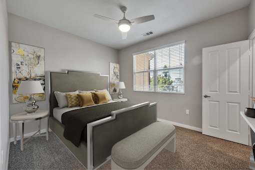 A bedroom with a bed, a bench, and a ceiling fan.