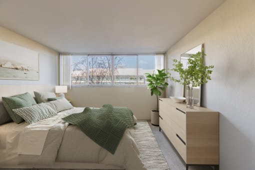 1-Bedroom Apartments in Redwood City, CA - Avenue Two - Bedroom with Carpet Flooring, Full-Size Bed, Nightstand with Lamp, Dresser, Houseplants, and Large Window at Avenue Two Apartments, Redwood City