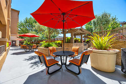 A red umbrella is in the middle of a table with chairs around it.