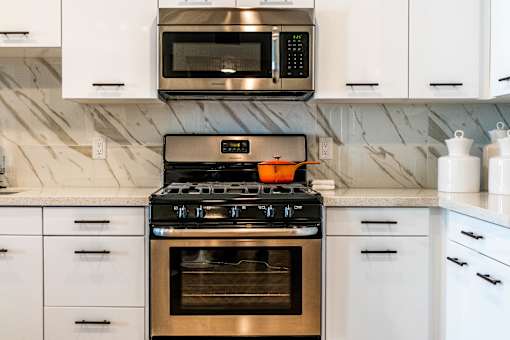 A modern kitchen with a stove top oven and microwave above it. at Baker Block, Costa Mesa, CA, 92626