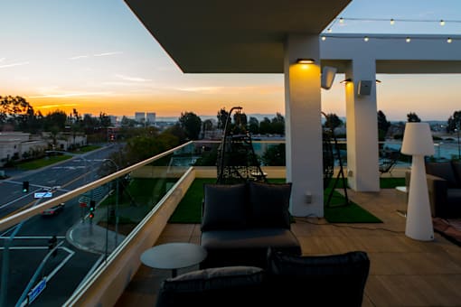 A balcony with a table and chairs overlooking a street at sunset. at Baker Block, California, 92626
