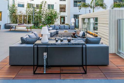 A modern outdoor seating area with a large grey sofa and a coffee table. at Baker Block, Costa Mesa, California
