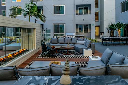 A modern outdoor seating area with grey couches and a fire pit. at Baker Block, Costa Mesa, California