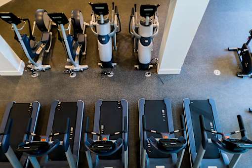 A row of treadmills and exercise bikes are lined up in a gym. at Baker Block, California