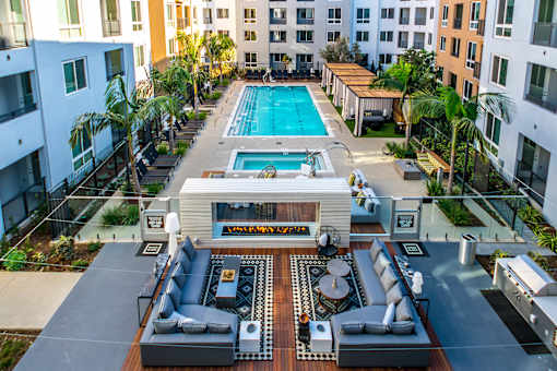 A large outdoor area with a pool, seating, and a kitchen area. at Baker Block, Costa Mesa, CA, 92626