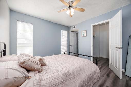 A bedroom with a bed, pillows, and a ceiling fan.
