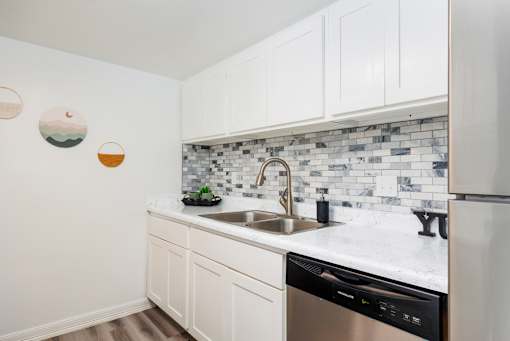A kitchen with white cabinets and a black dishwasher.