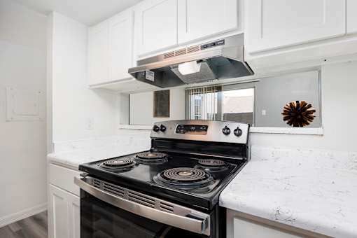 A modern kitchen with a stove top oven and white cabinets.