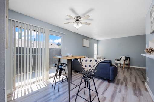 A living room with a blue couch and a dining table with chairs.
