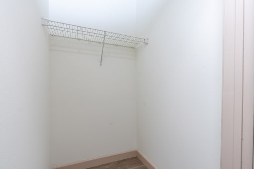 an empty room with a white wall and a wire rack on the wall