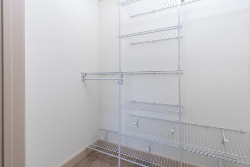 an empty closet with white walls and white wire shelves