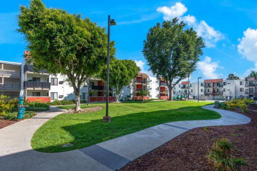 a park with grass and trees in front of apartment buildings