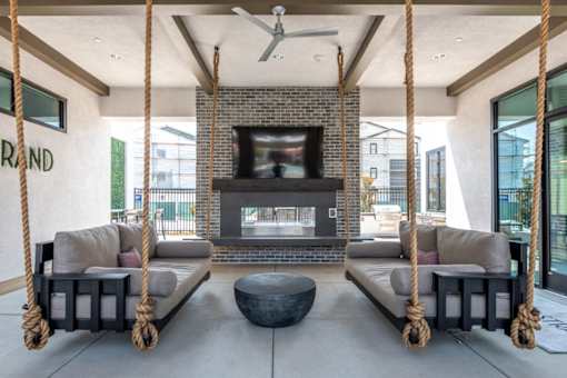 Outdoor California Room with a fireplace and two hanging sofas.