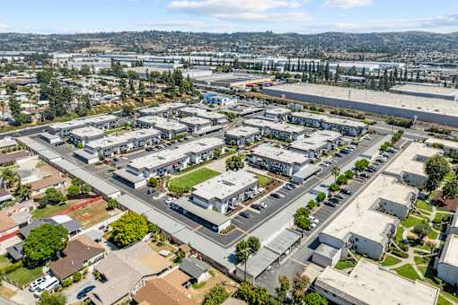 A large aerial view of a suburban area with buildings, roads, and a body of water in the distance.