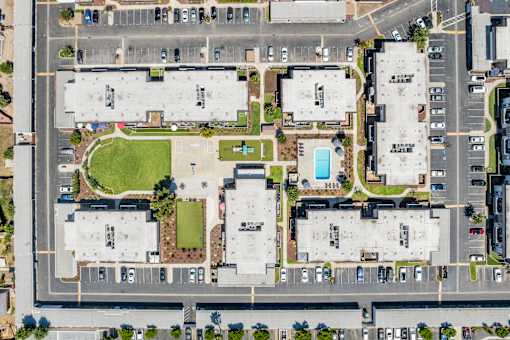 An aerial view of a parking lot with a large building and a pool.