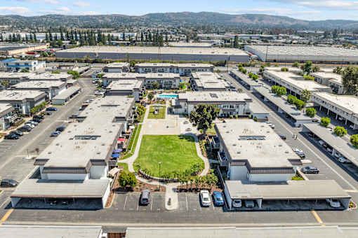 A large parking lot with several buildings surrounding a green space.