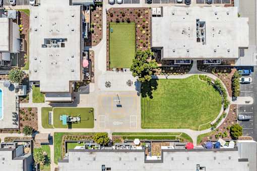A large grassy area with a basketball court in the middle of a parking lot.