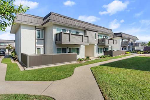 A modern apartment building with a well-maintained lawn in front.