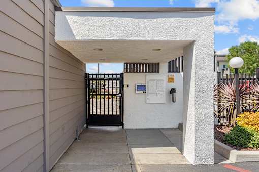 A white building with a black gate and a sign on the wall.