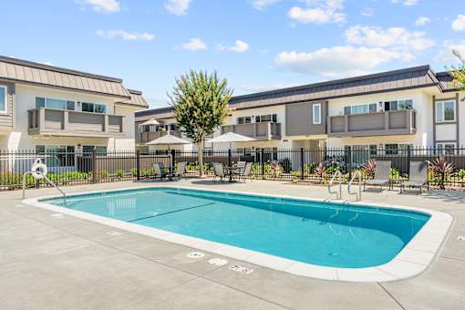 A swimming pool in front of a building with a fence around it.
