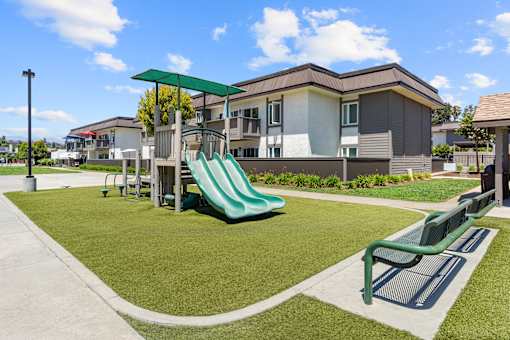 A playground with a green slide and a green bench.
