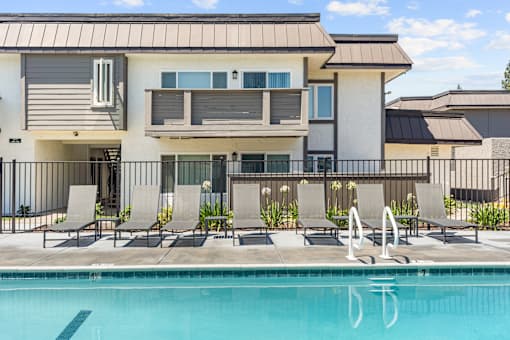 A swimming pool in front of a modern two-story apartment building.