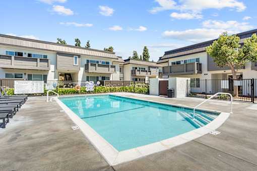 A swimming pool in a sunny day surrounded by apartment buildings.