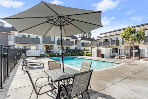 A patio with a table and chairs and an umbrella over it.