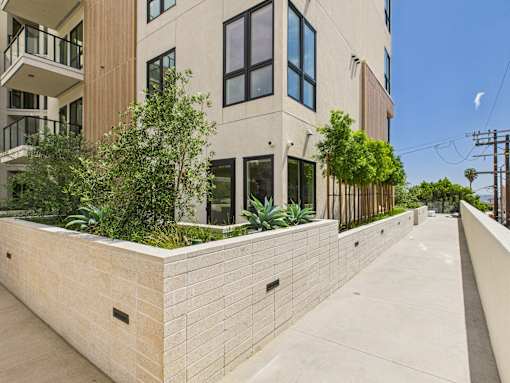 A modern building with a concrete wall and green plants at Skyview Sunset Apartments, Los Angeles 90046