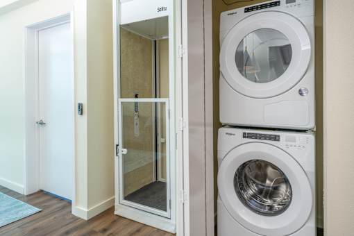 A white washing machine is stacked on top of another white washing machine.