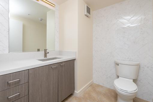 A bathroom with a toilet, sink, and mirror.