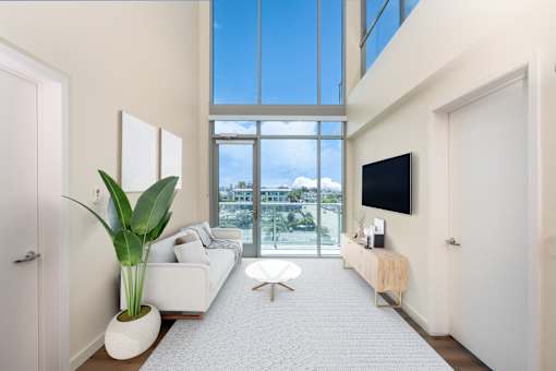 A modern living room with a large window and a flat screen TV mounted on the wall.