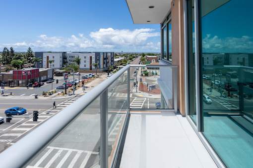 A balcony overlooks a street with cars and buildings.