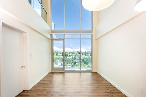 A large, empty room with a view of the outdoors through a large window.