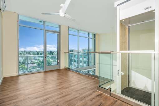 A room with a ceiling fan and a view of the city.