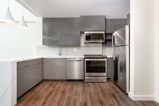 A modern kitchen with stainless steel appliances and wooden floors.