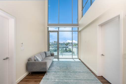 A living room with a grey couch and a large window.