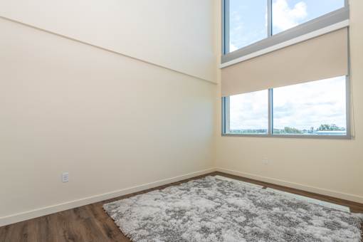 A room with a large rug and a window with a view of the sky.