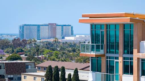 A modern building with a balcony overlooks a residential area.
