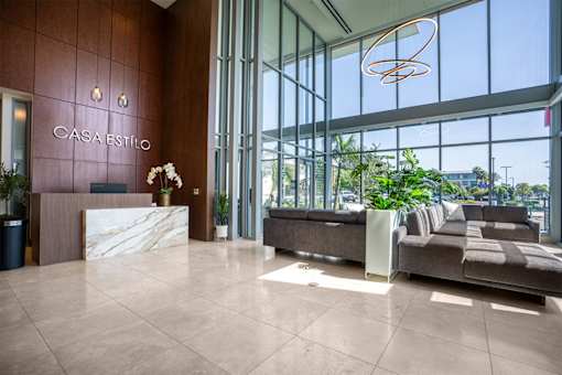 The image shows the lobby of a hotel named Casa Estilo with a reception desk and a sofa.