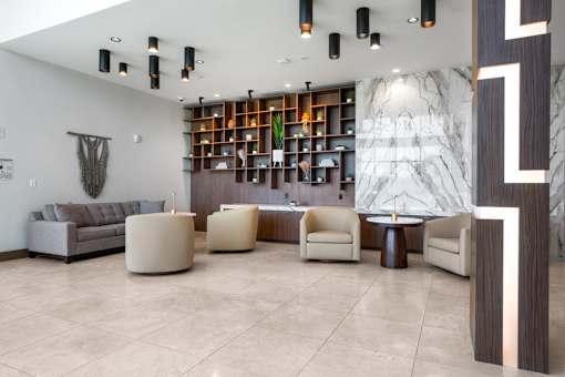 A modern living room with a grey sofa, a wooden bookshelf, and a marble wall.