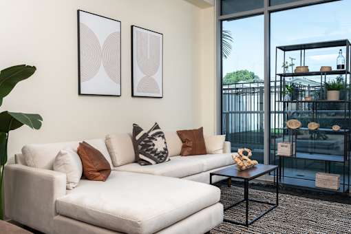 A white couch with pillows and two framed artworks on the wall.