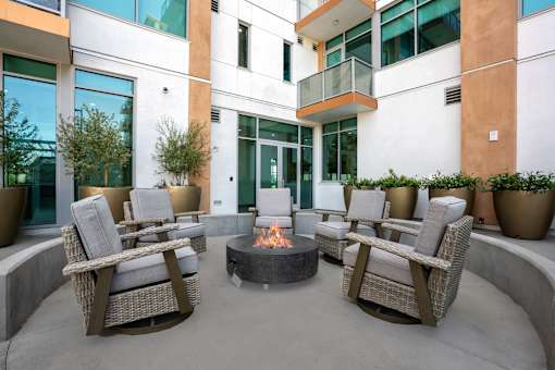 A patio with a fire pit and chairs.