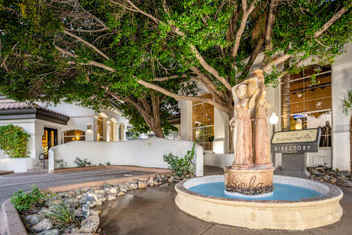 A statue of a woman stands in the middle of a fountain.