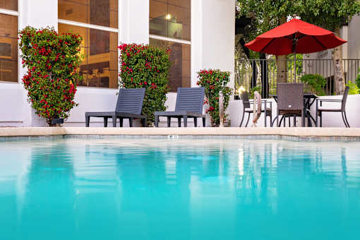 A pool with chairs and a red umbrella.