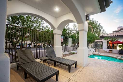 Two lounge chairs are placed under a white arched structure.
