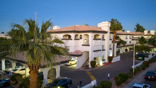 A large white building with a red tile roof and a palm tree in front.