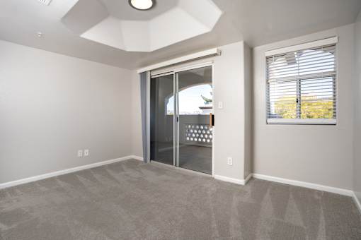 A room with a carpeted floor and a sliding glass door leading outside.