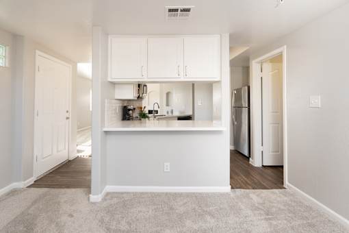 A kitchen area with white cabinets and appliances.