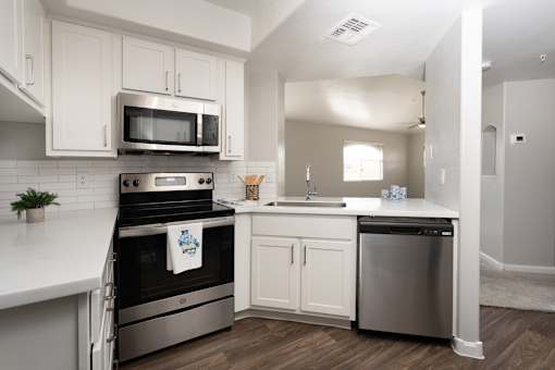 A modern kitchen with white cabinets and stainless steel appliances.